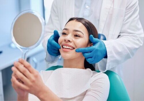Young woman smiling and looking at teeth after receiving dental care in Peoria IL