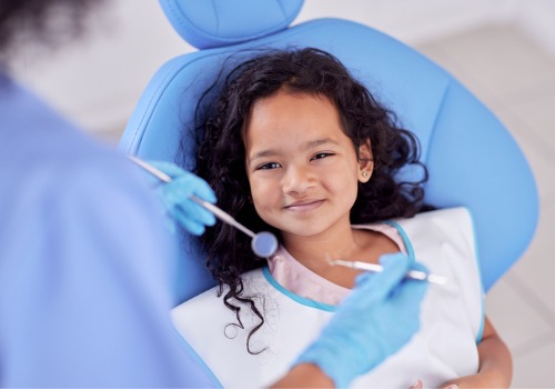 A young girl smiles at her dentist after having a basic cleaning, which is one of many options River City Family Dentistry offers in addition to Invisalign in East Peoria IL