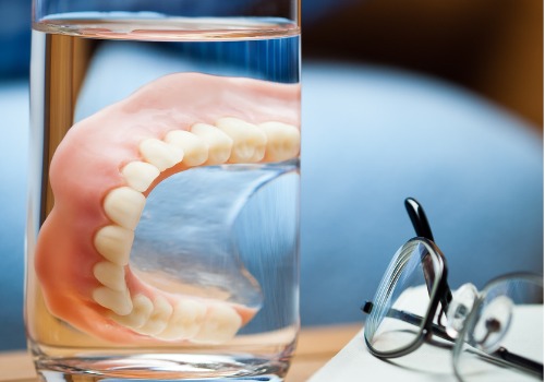Dentures are seen soaking in a glass. River City Family Dentistry offers dentures in Morton IL.